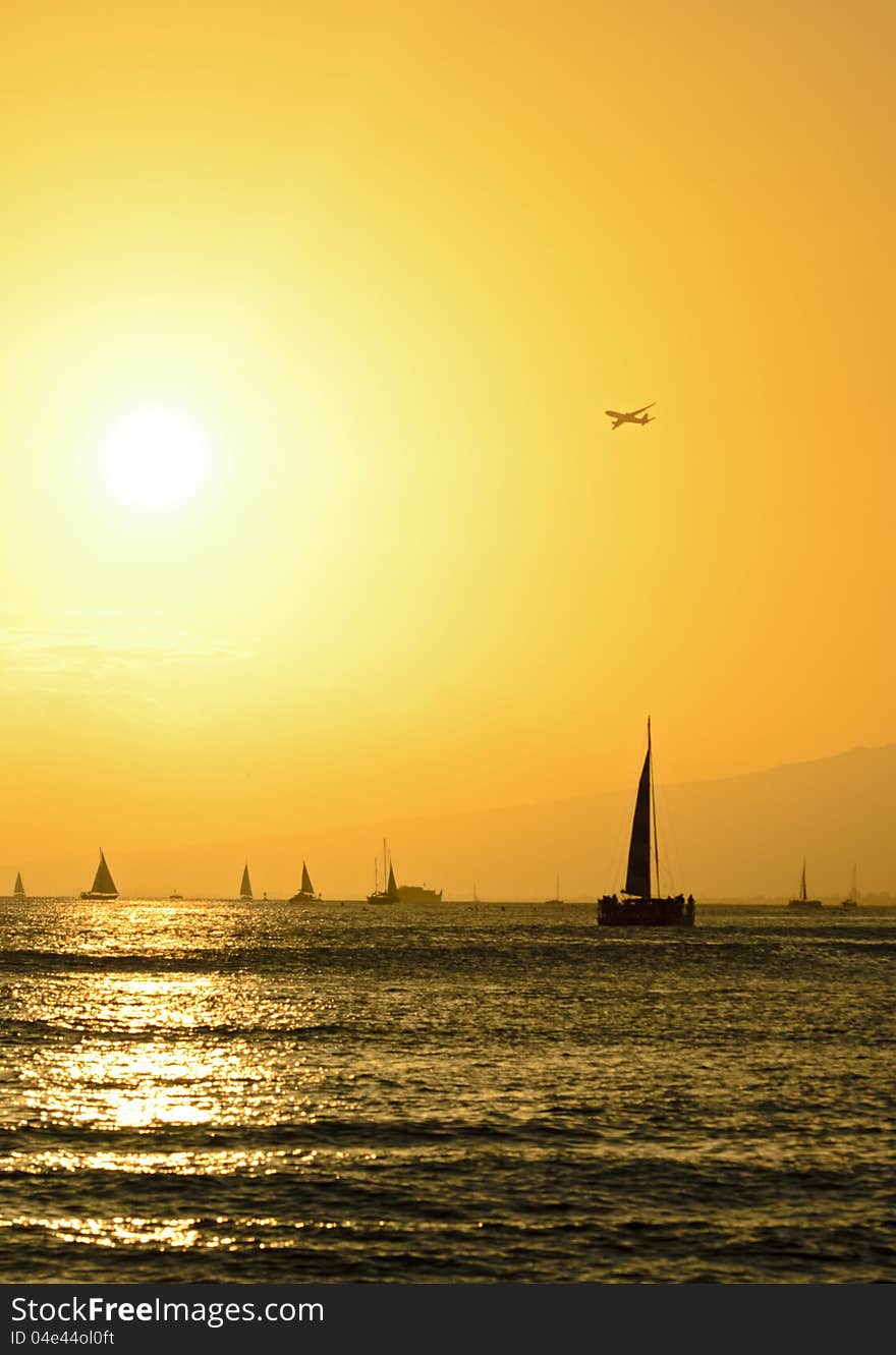 Sailboats and airplane over Hawaiian sunset at Waikiki Beach, Oahu, Hawaii