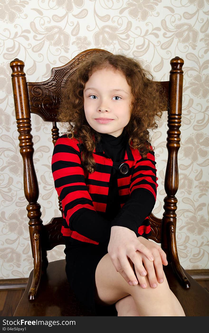 Portrait of ctue little girl sitting on a chair