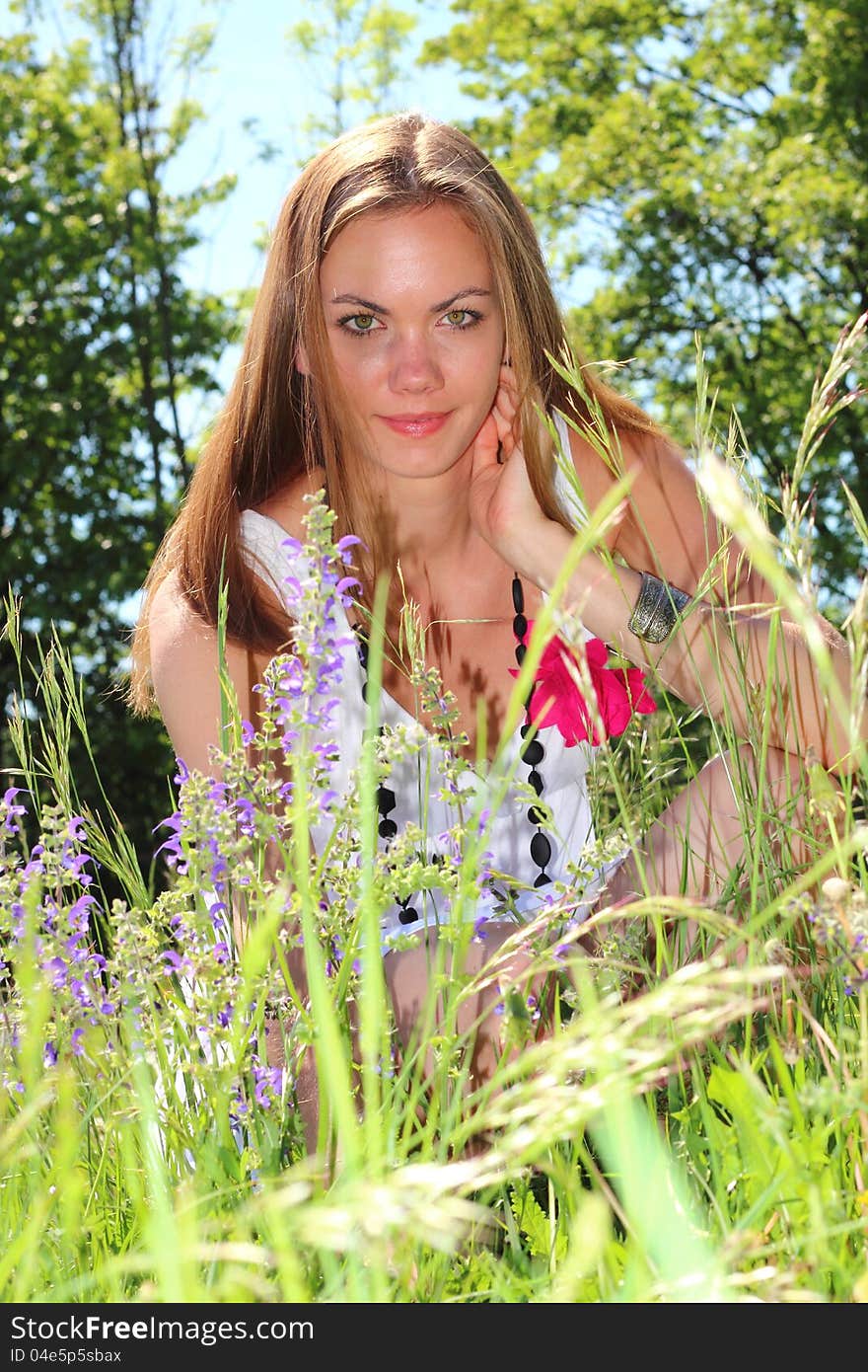 Beautiful young woman between flowers in the nature