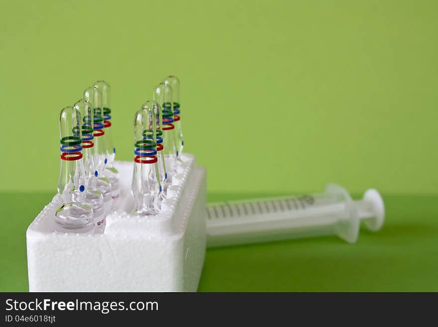 Closeup view of  medical vitamin ampules for syringes on green background. Closeup view of  medical vitamin ampules for syringes on green background.