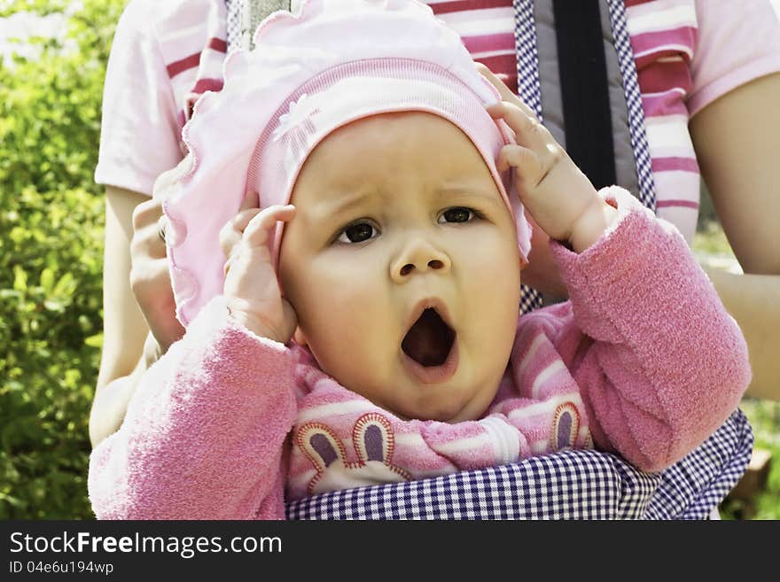 Closeup portrait of yawning baby girl in a pink jacket on the street. Closeup portrait of yawning baby girl in a pink jacket on the street