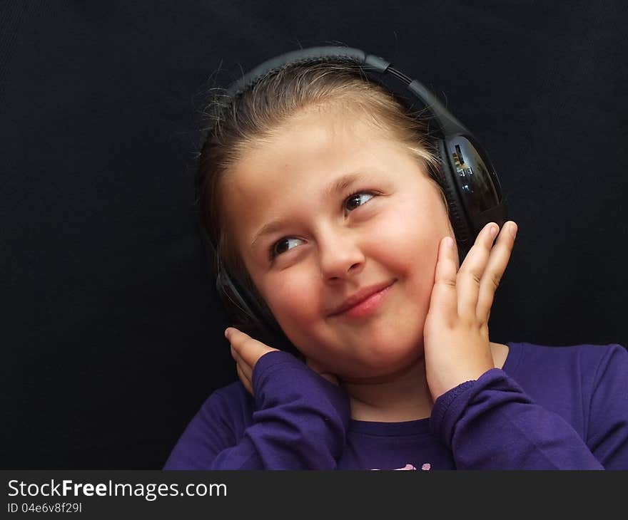 Little girl is listening music with headphone