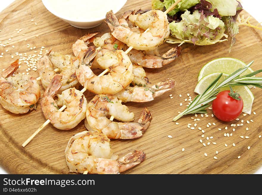 Grilled shrimp with a salad on a wooden plate