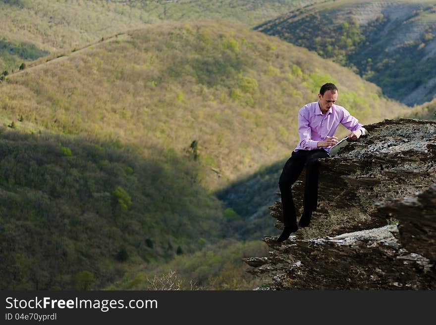 Man writes in notepad sitting on stone. Man writes in notepad sitting on stone