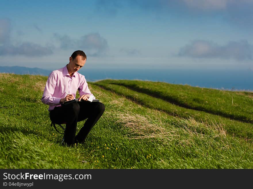 Man writes in paper sitting on mountain. Man writes in paper sitting on mountain