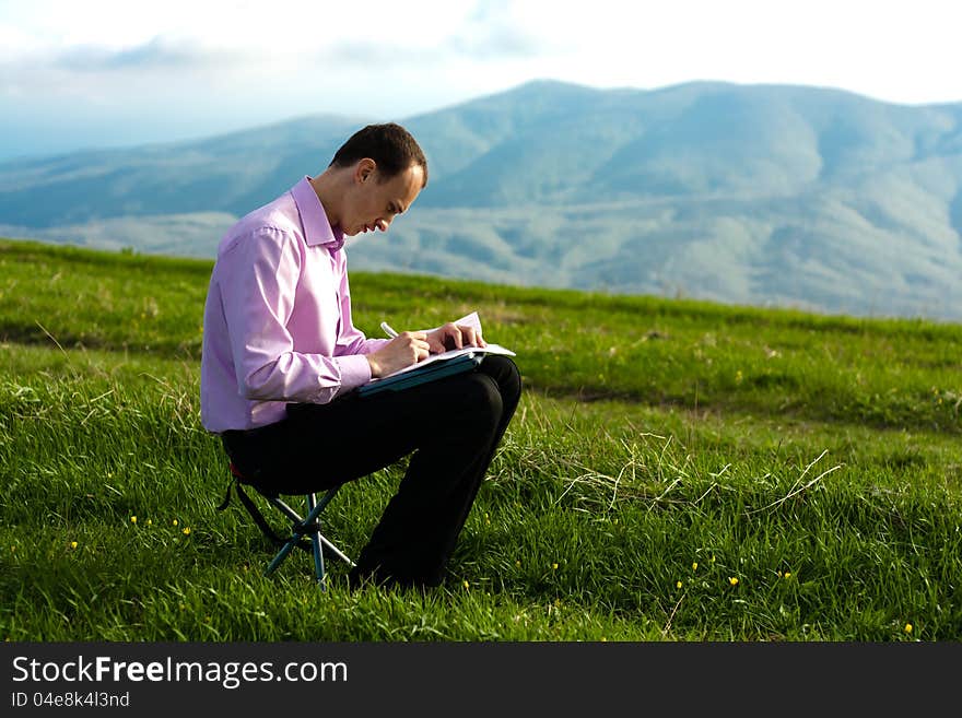 Man writes in paper sitting on mountain. Man writes in paper sitting on mountain