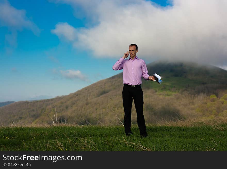 Man speaks on telephone and takes notepad staying on mountain. Man speaks on telephone and takes notepad staying on mountain