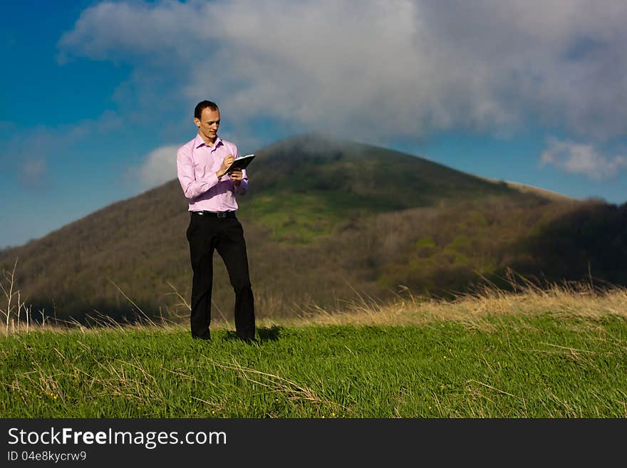 Man writes in notepad sitting on mountain. Man writes in notepad sitting on mountain