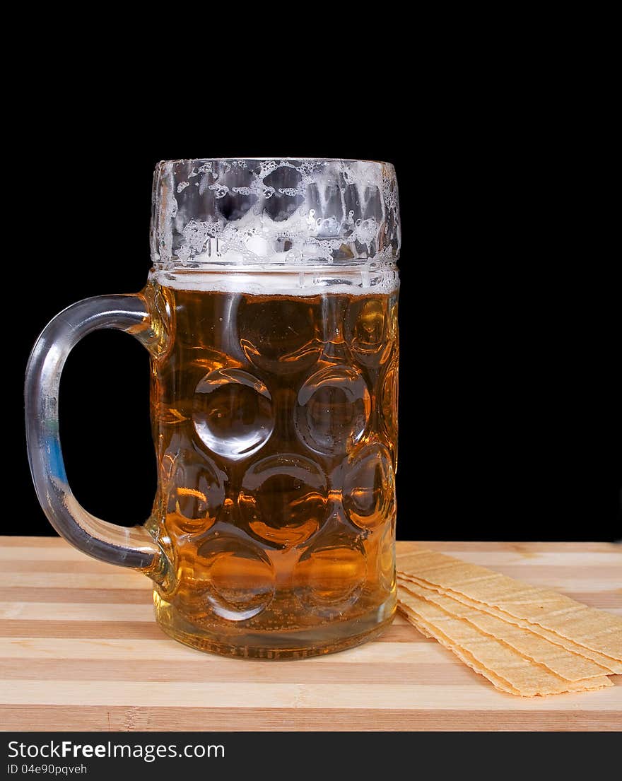 Glass of fresh beer with foam and chips on a black background