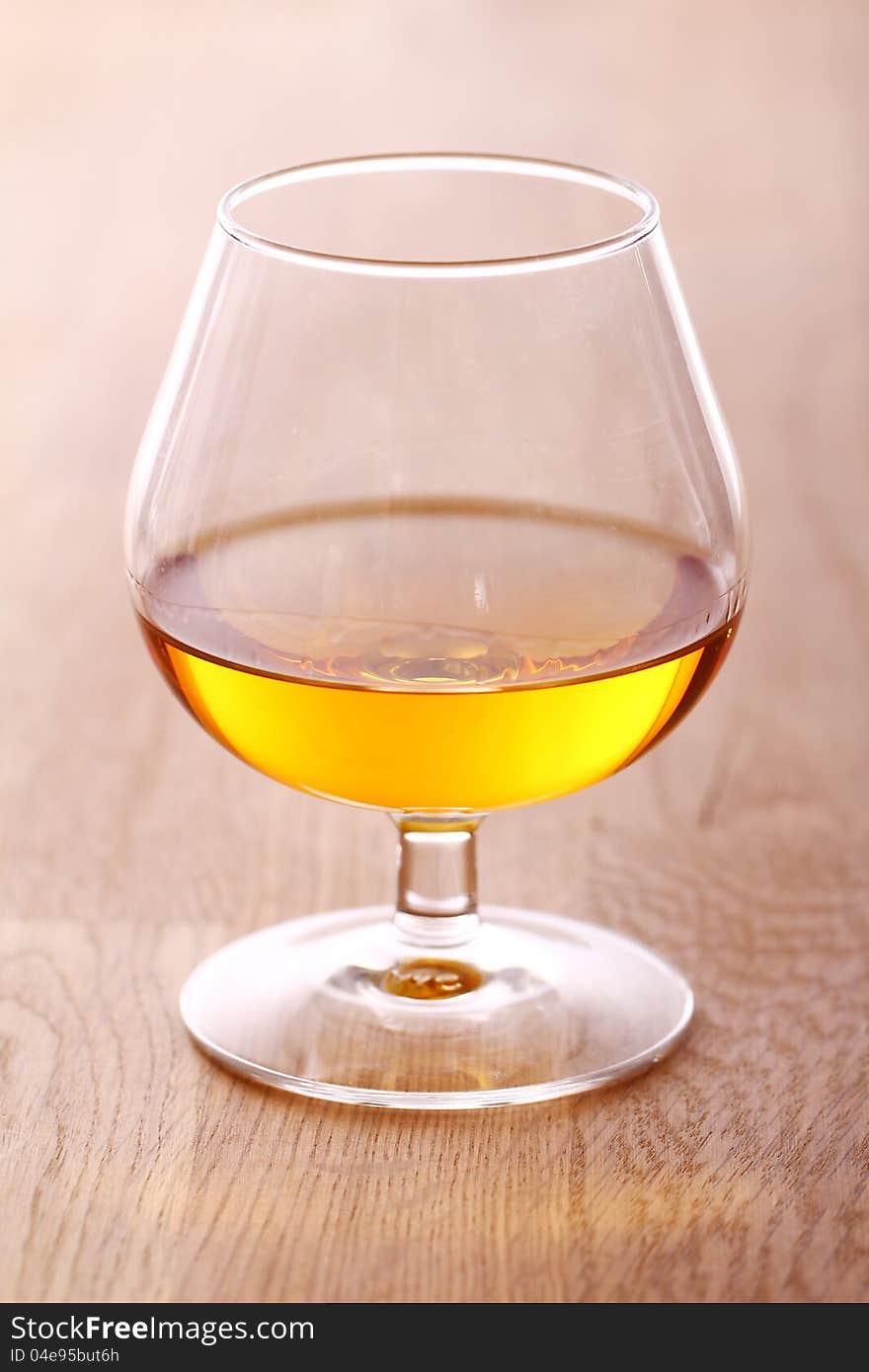 Glass of cognac over wooden surface