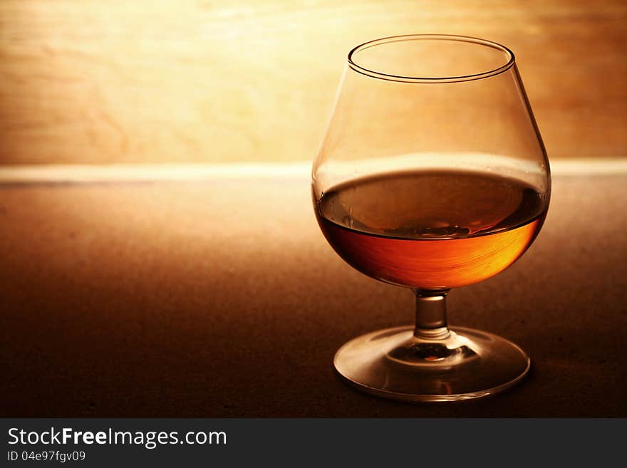 Glass of cognac over wooden surface