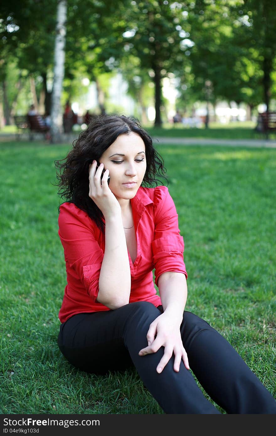 Girl with the phone sitting on the grass