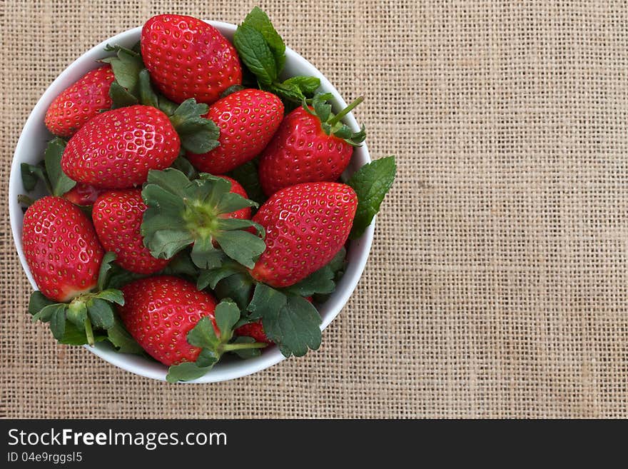 Strawberries in a bowl on burlap with space for text. Strawberries in a bowl on burlap with space for text