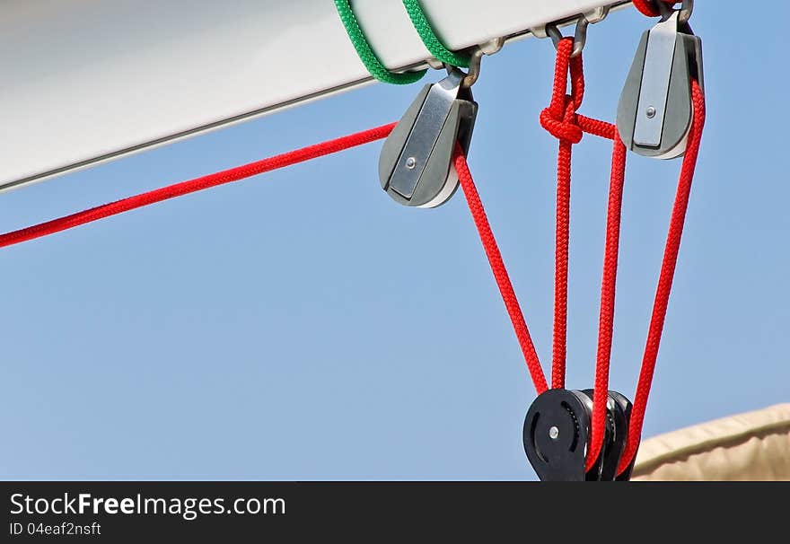 Sailing rigging. Blocks and red cords. Detail of yacht. Ropes of sailboat - tackles on the rigging yacht. Yachting equipping - pulleys blocks.