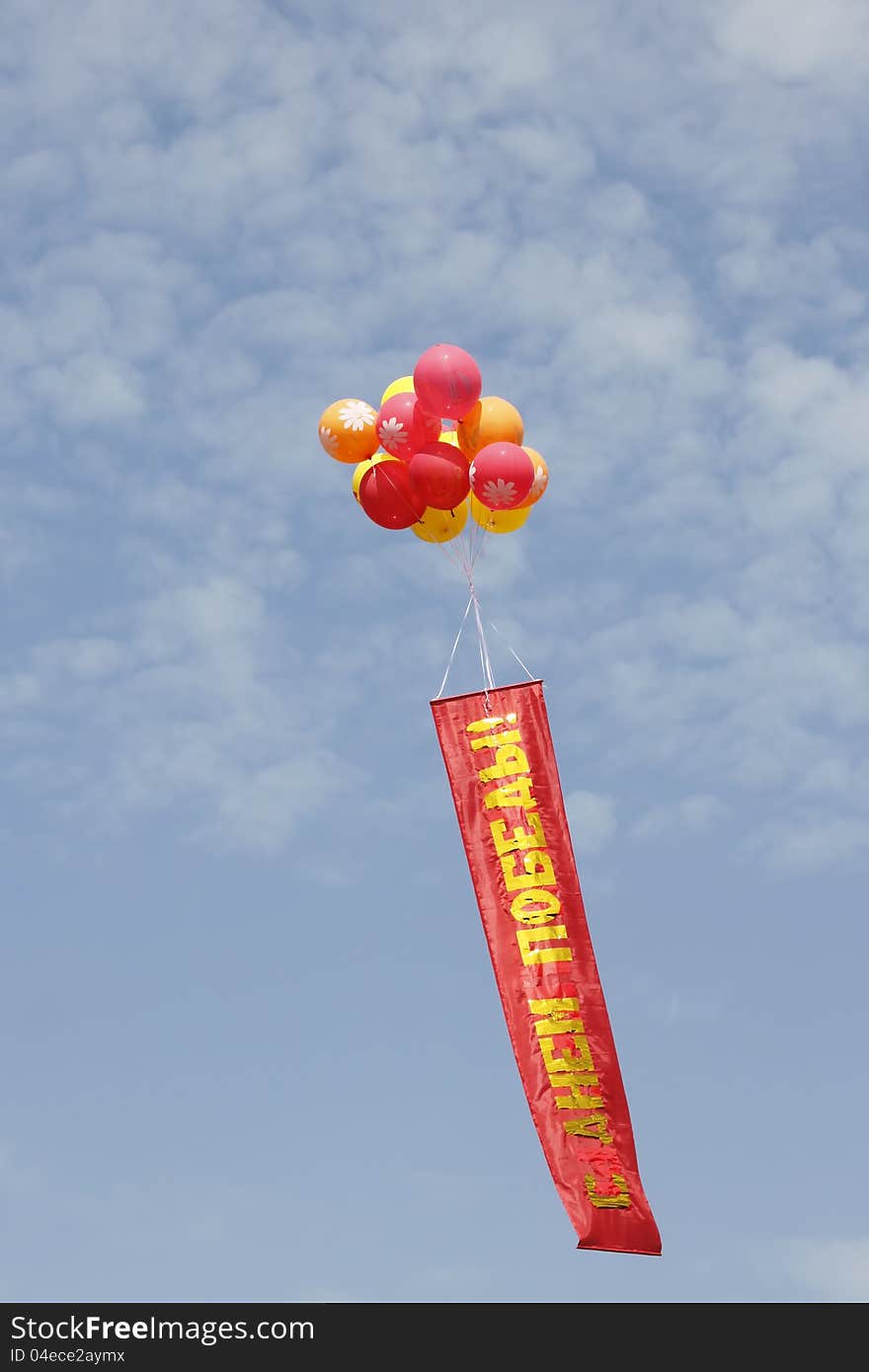 Multi-colored balloons with a banner against the blue sky with clouds. Multi-colored balloons with a banner against the blue sky with clouds