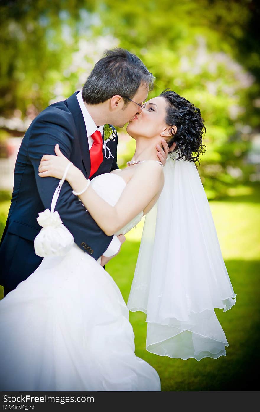 Bride and groom in a park kissing on green backgro