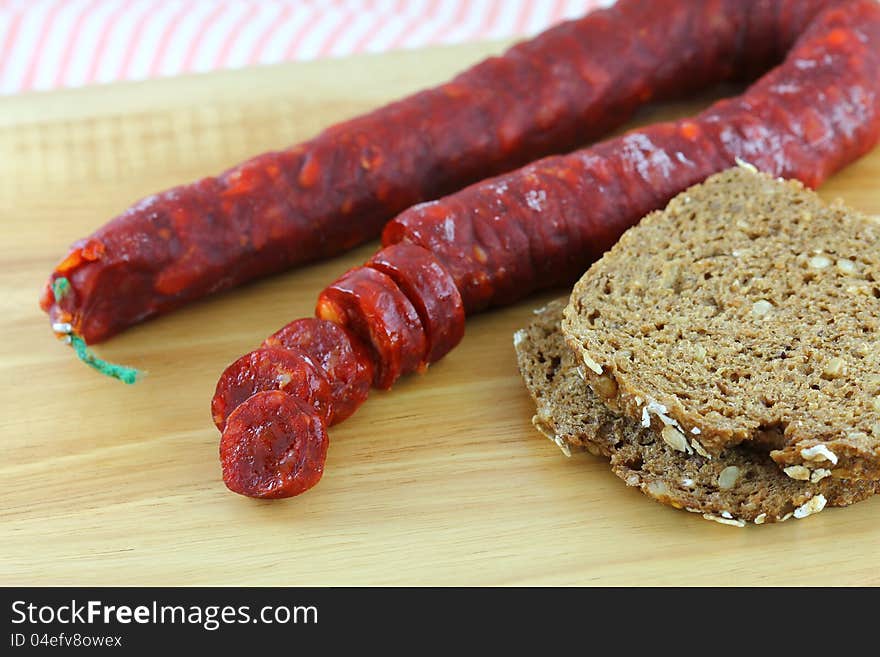 Spicy Spanish Chorizo (Cured Paprika sausage) with wholewheat bread on a wooden cutting board. Spicy Spanish Chorizo (Cured Paprika sausage) with wholewheat bread on a wooden cutting board