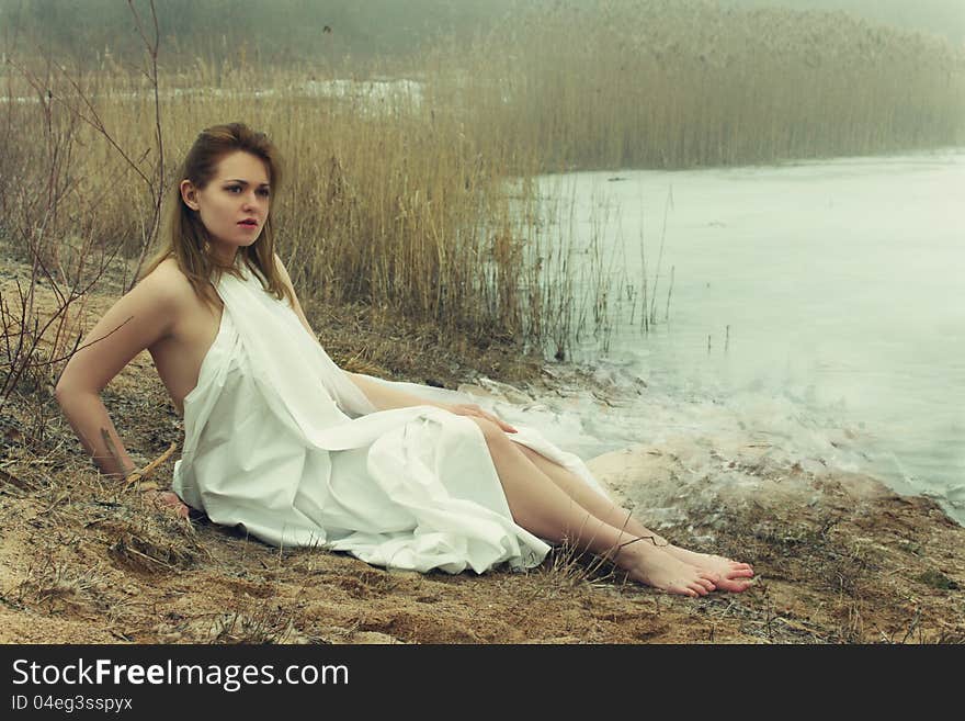 Woman in white dress in the winter on the rushy lake