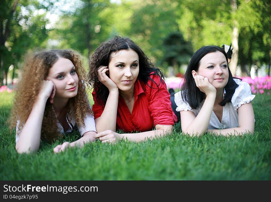 Portrait of three friends on the grass in the park