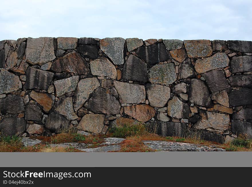 Stonewall made of hewn granite boulders with horizontal edge and sky above. Stonewall made of hewn granite boulders with horizontal edge and sky above