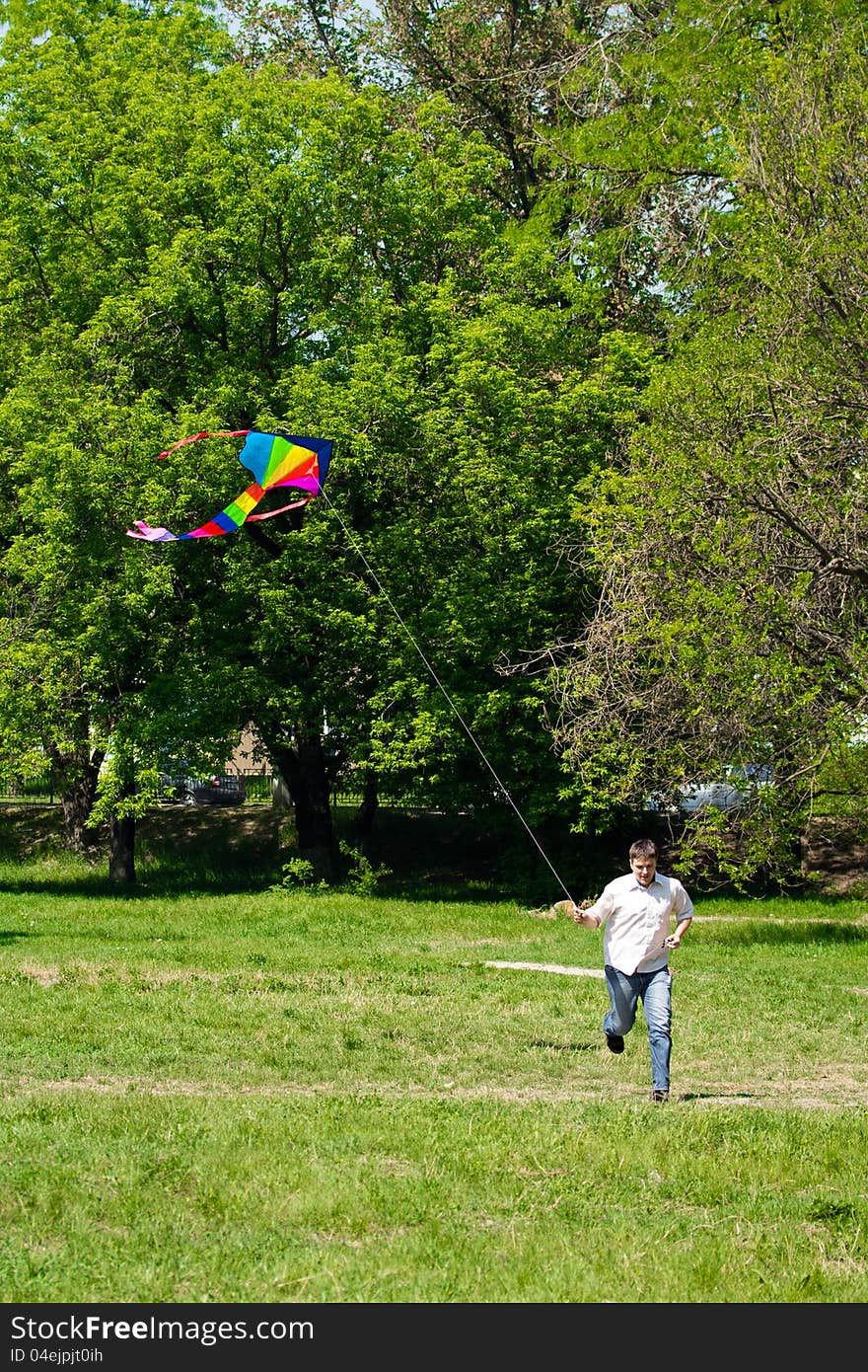 Man running over a green meadow in summer; he fly a kite. Man running over a green meadow in summer; he fly a kite