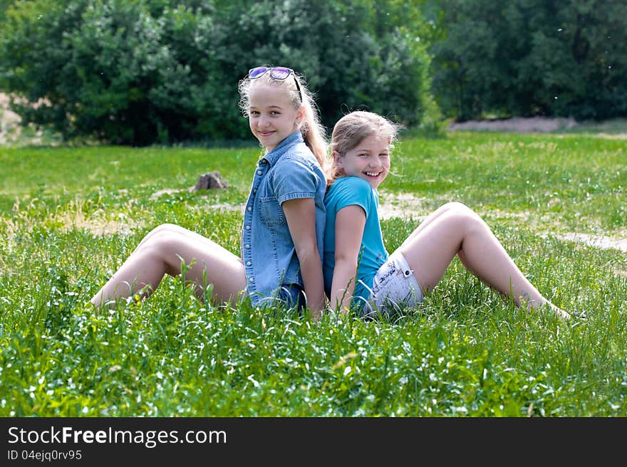 Two cheerful girls sitting on grass. Two cheerful girls sitting on grass