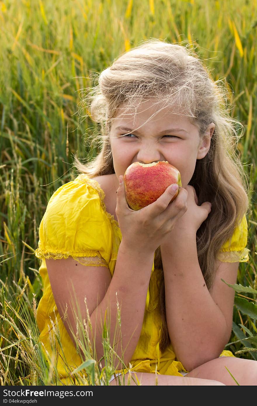 Portrait of a young beautiful girl with red apple at the wheat field. Portrait of a young beautiful girl with red apple at the wheat field