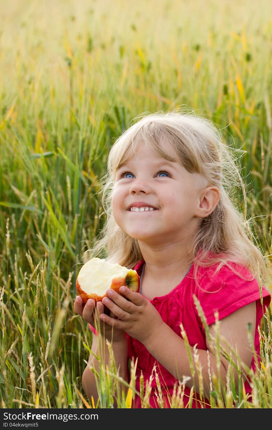 Beautiful blue-eyed girl biting an apple in a wheat field. Beautiful blue-eyed girl biting an apple in a wheat field