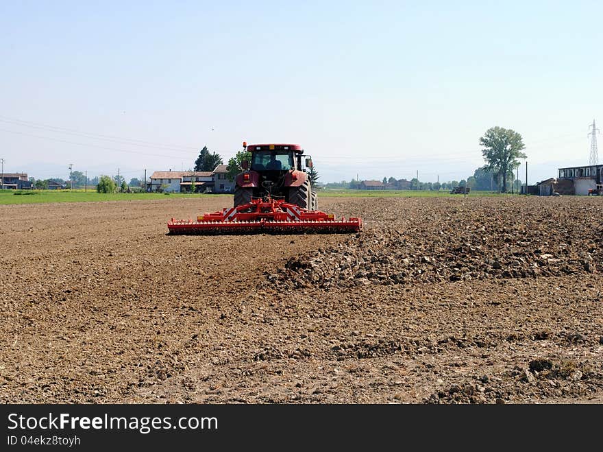 Red tractor prepares soil