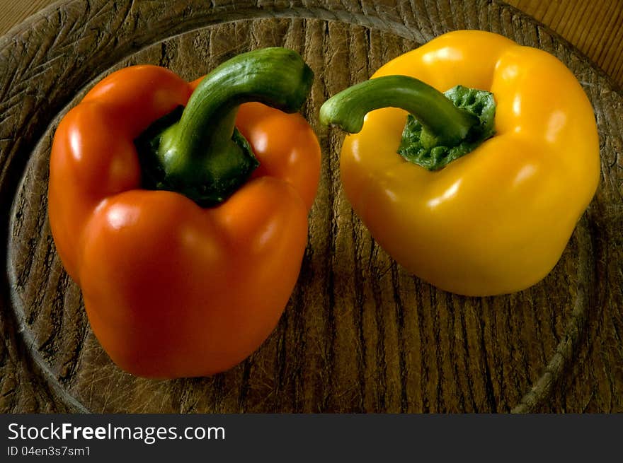 Two sweet peppers on a wooden board.