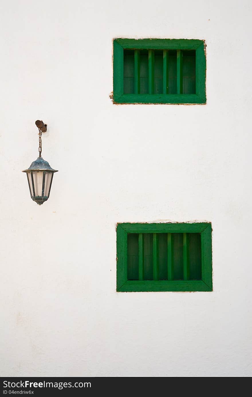 Green windows and light on white wall. Typical Lanzarote island architecture (Canary Islands). Green windows and light on white wall. Typical Lanzarote island architecture (Canary Islands).