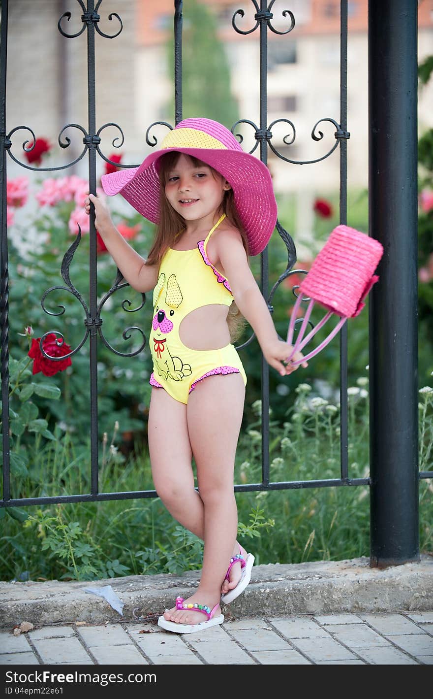 Picture a cute little girl in hat posing with beautiful flowerbeds. Picture a cute little girl in hat posing with beautiful flowerbeds