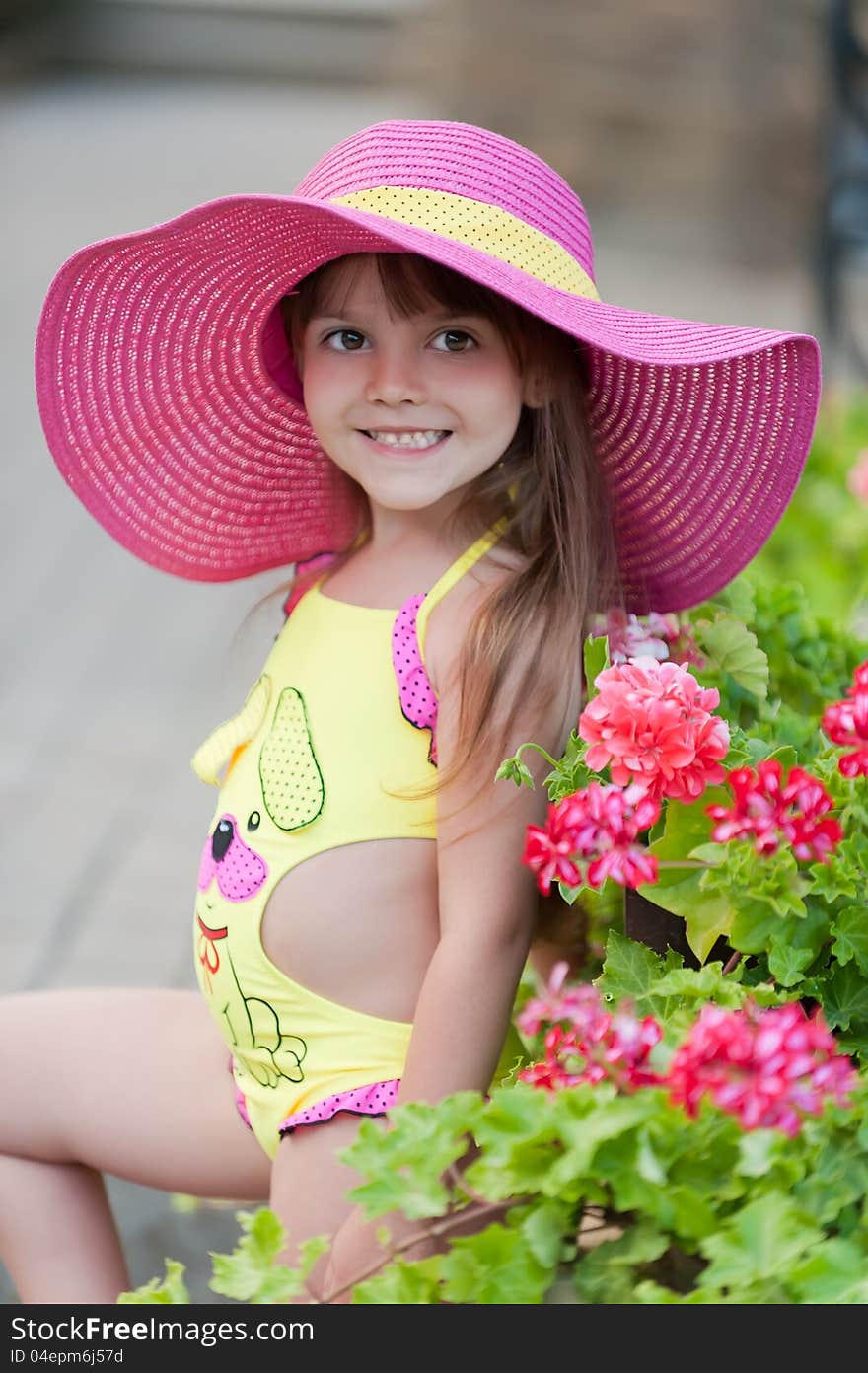 Little girl in hat posing with beautiful flowerbeds. Little girl in hat posing with beautiful flowerbeds