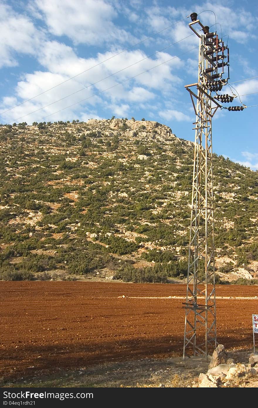 Field an mountain with a elektric power mast in front. Field an mountain with a elektric power mast in front