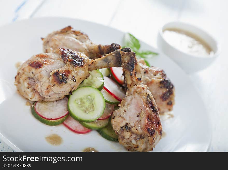 Ginger and lemon chicken drumsticks on a cucumber and radish salad. Ginger and lemon chicken drumsticks on a cucumber and radish salad