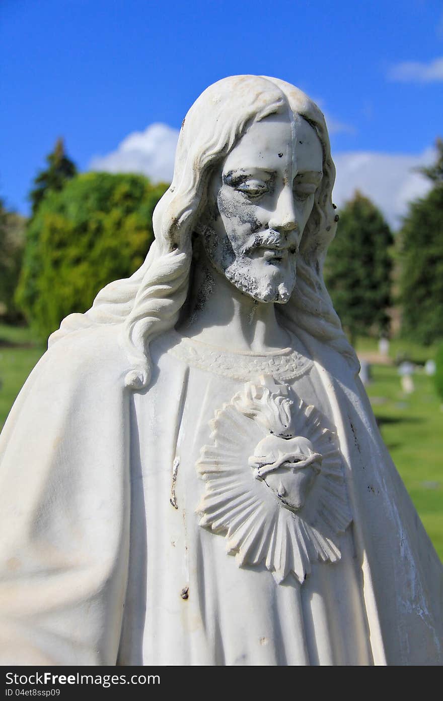 Image of a statue of Jesus Christ in a cemetery, with trees in the background. Image of a statue of Jesus Christ in a cemetery, with trees in the background