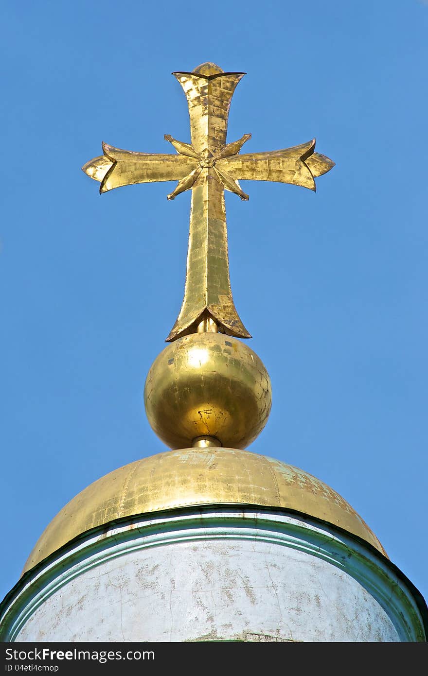 Gold cross on the dome of the old temple lit the sun. Above the dome, blue sky. Gold cross on the dome of the old temple lit the sun. Above the dome, blue sky.