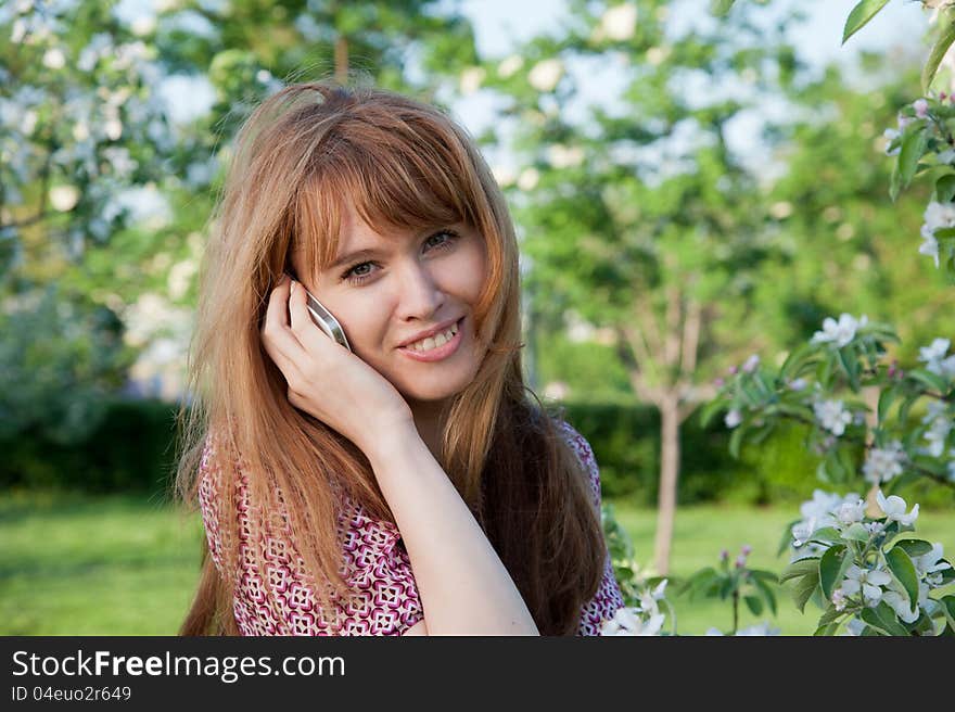 Woman talk by phone in the park near the apple tree. Woman talk by phone in the park near the apple tree