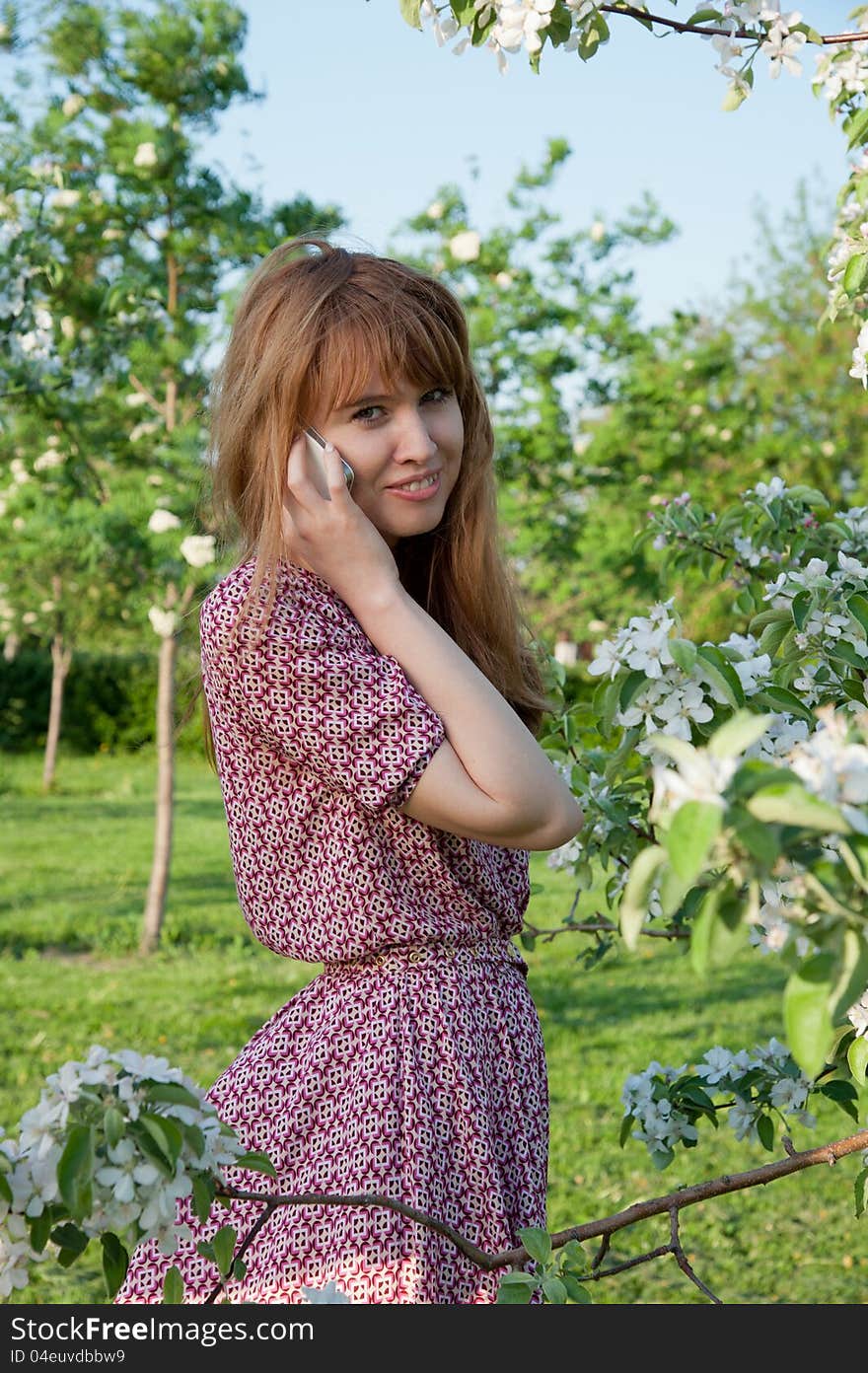 Woman talk by phone in the park near the apple tree. Woman talk by phone in the park near the apple tree