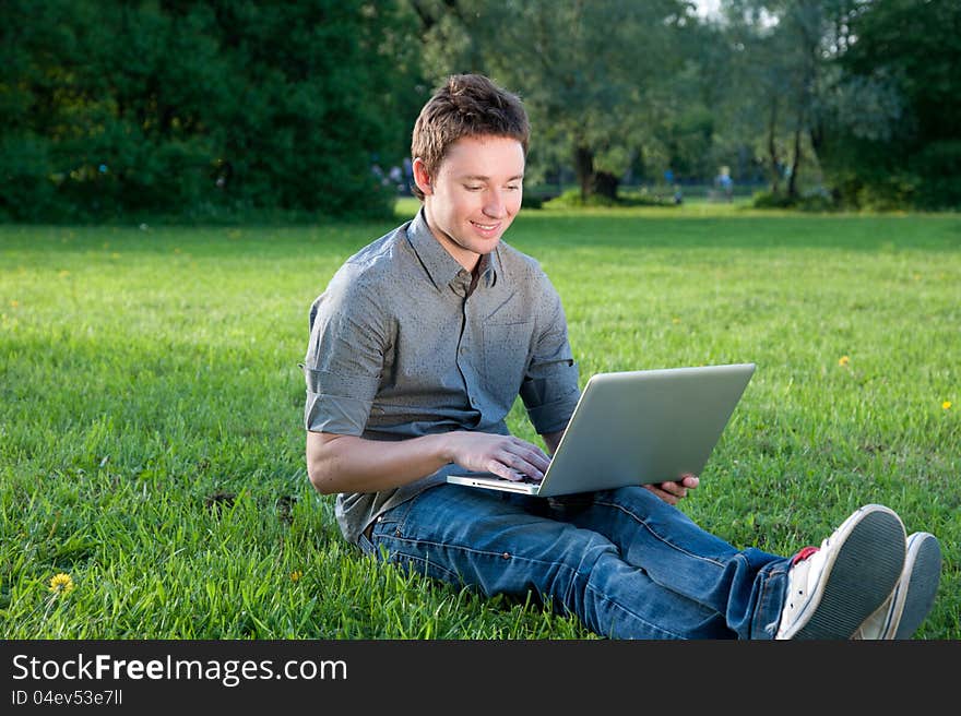 Man sits on the grass with laptop. Man sits on the grass with laptop