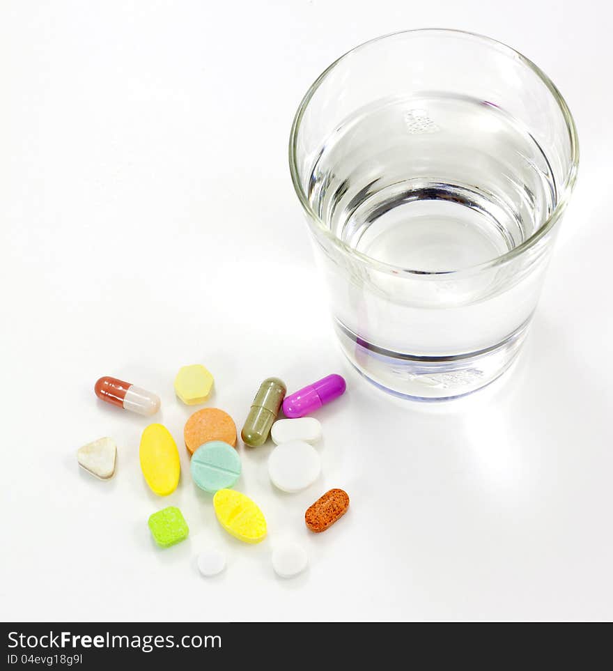 Glass of water and pills on white