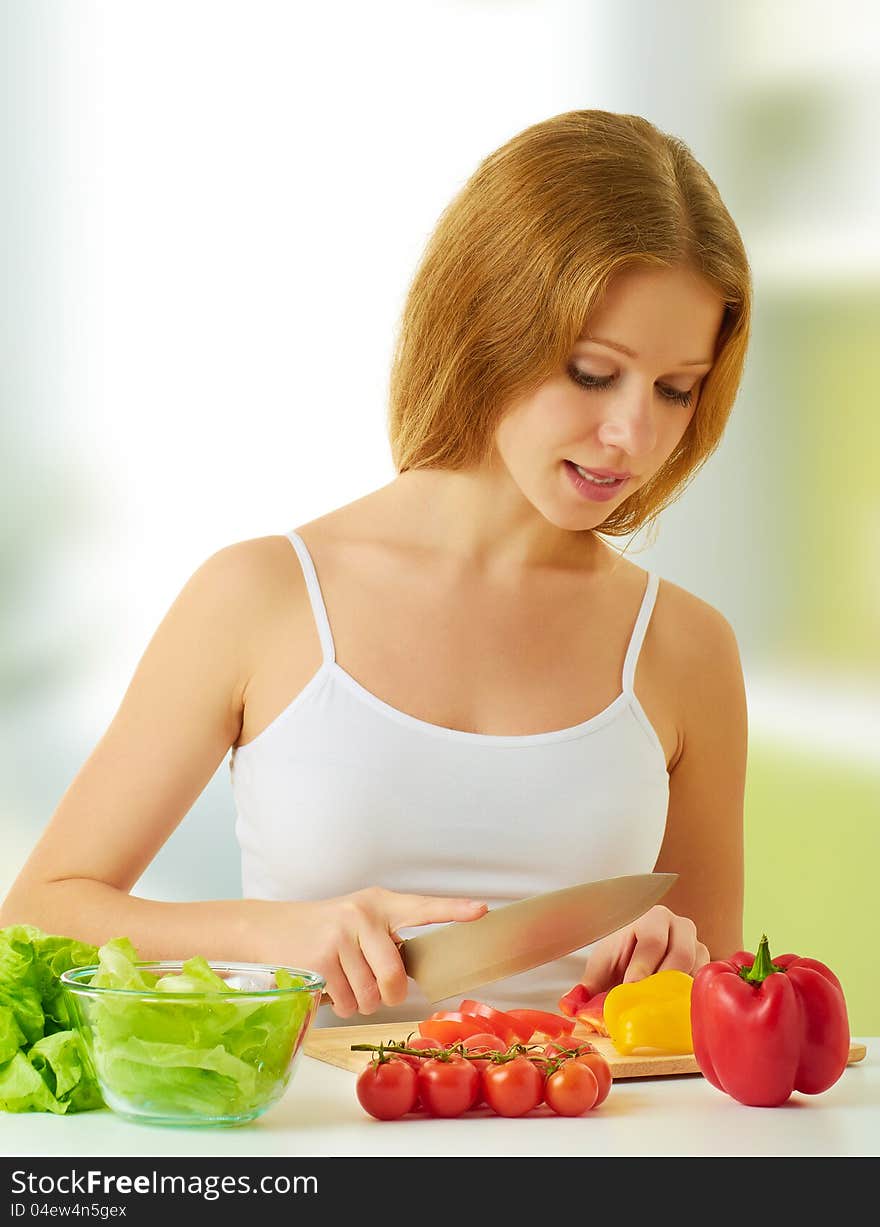 Beautiful young woman, a housewife preparing dinner vegetable salad in the kitchen at home