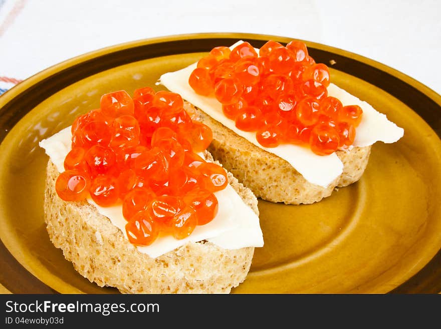 Red caviar sandwich on small ceramic plate