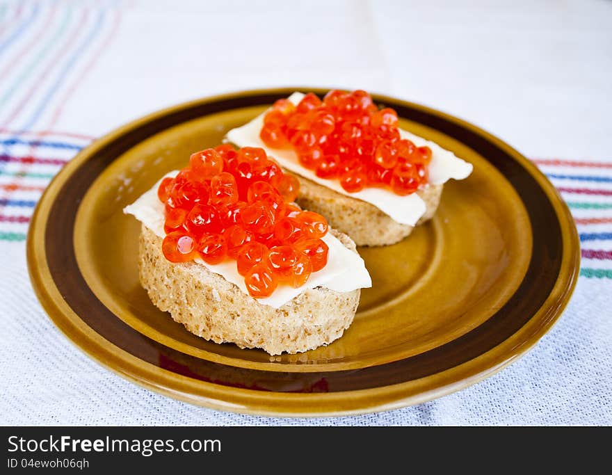 Red caviar sandwich on small ceramic plate