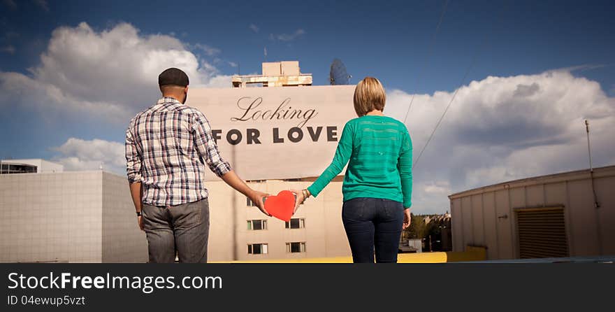 Engaged couple in front of looking for love sign. Engaged couple in front of looking for love sign