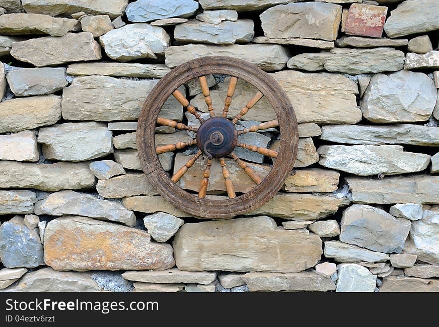 Vintage spinning wheel against stone wall background. Vintage spinning wheel against stone wall background