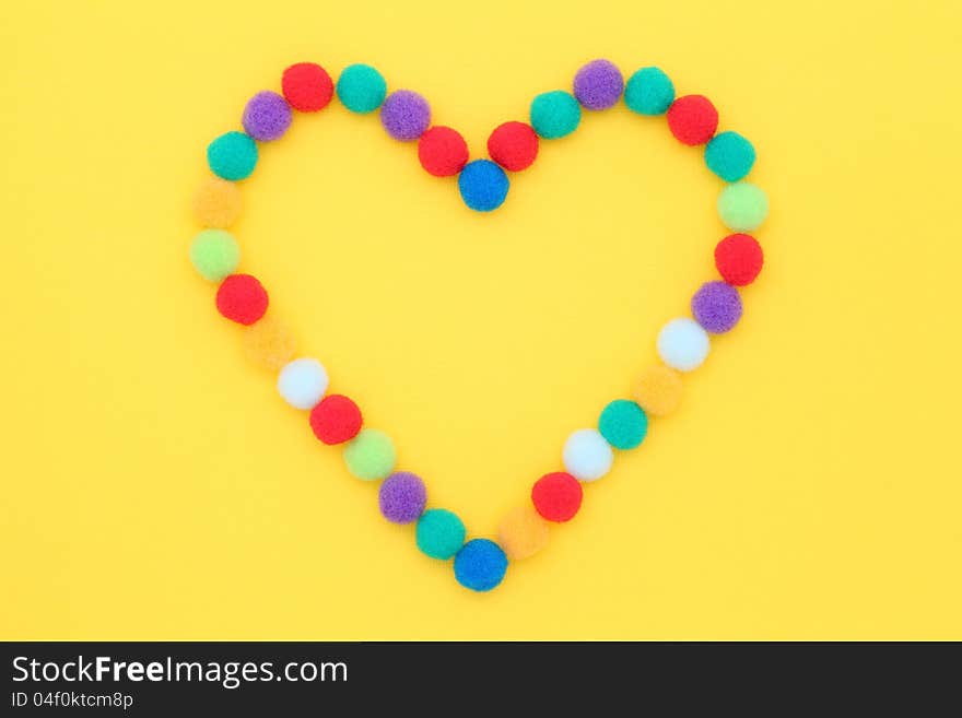 Colorful cotton balls on yellow background