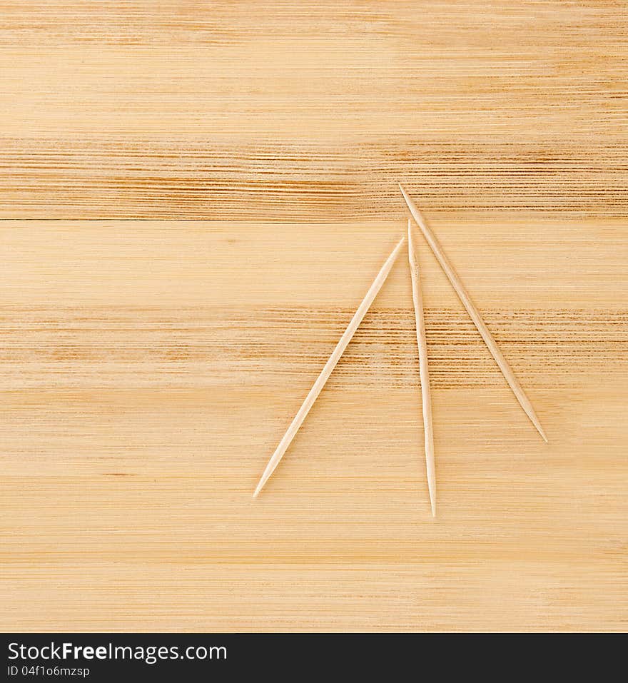 Three toothpicks on a light wooden table. Three toothpicks on a light wooden table