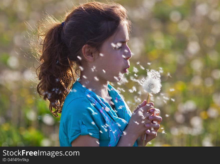 Young girl blows a dandelion