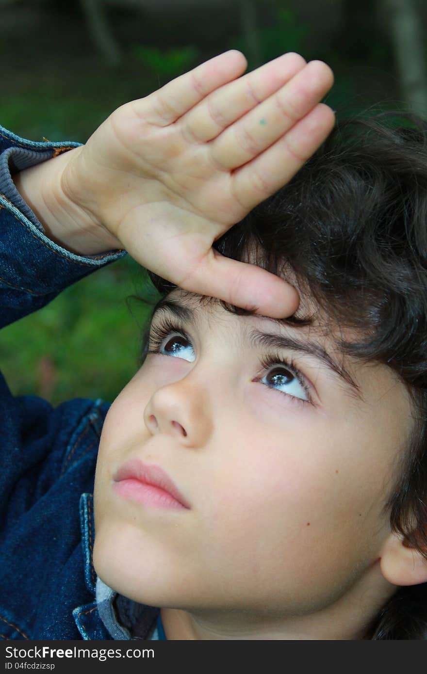 Close portrait of a beautiful boy with eyes lifted up and resting his hand on forehead. Close portrait of a beautiful boy with eyes lifted up and resting his hand on forehead